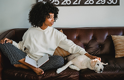 woman sitting on couch watching dog